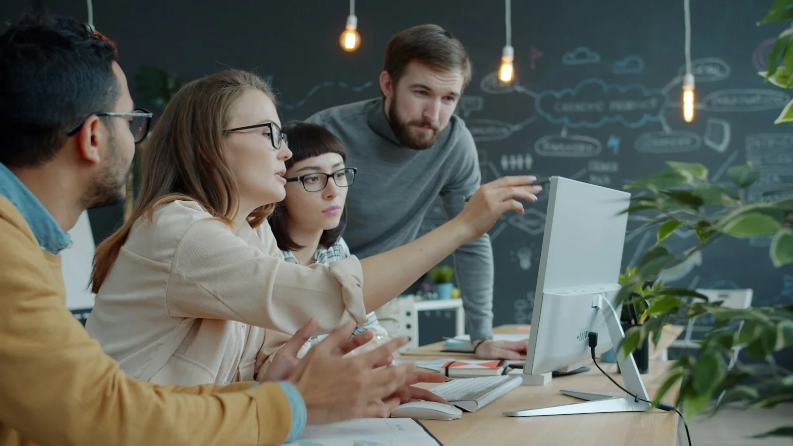 Colleagues collaborating around a computer during an office discussion